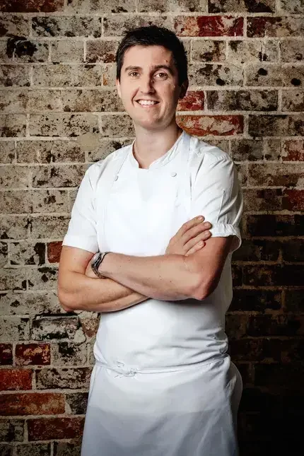 Chef Josh Niland against a brick background.