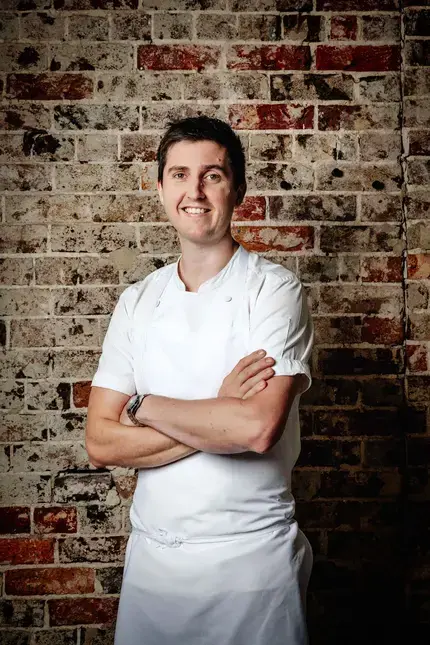 Chef Josh Niland against a brick background.