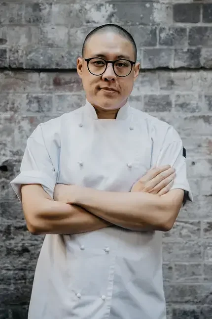Chef Dan Hong in chef whites with his arms folded.