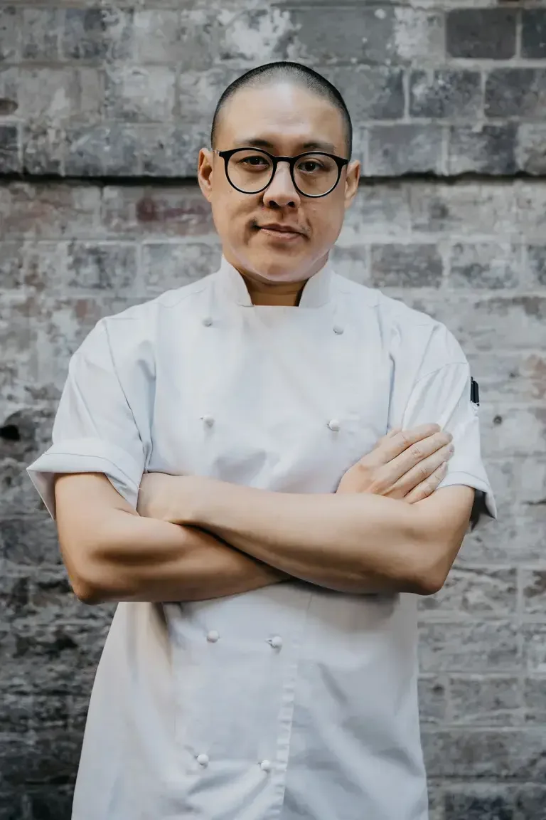Chef Dan Hong in chef whites with his arms folded.