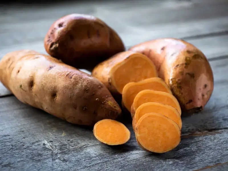 A pile of sweet potatoes, some sliced.