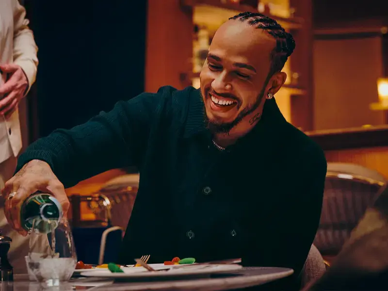 Lewis Hamilton pouring S.Pellegrino into a glass.