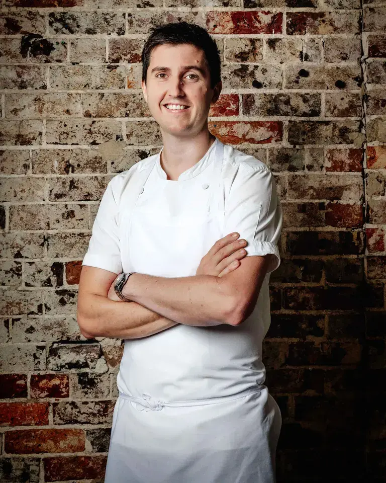 Chef Josh Niland against a brick background.