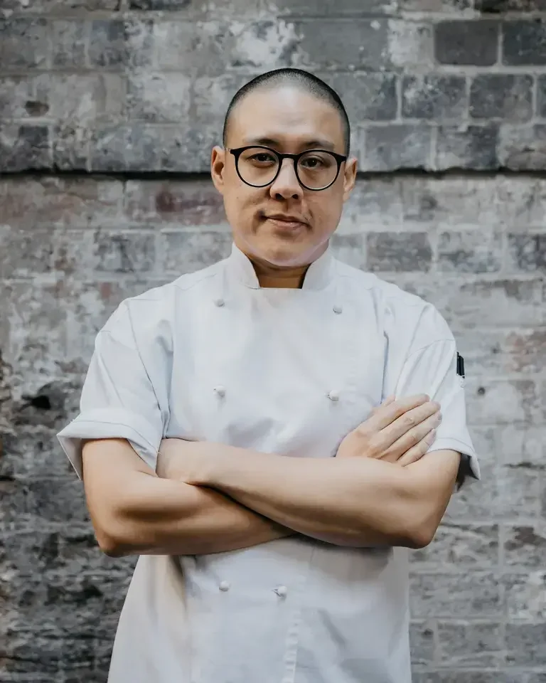 Chef Dan Hong in chef whites with his arms folded.