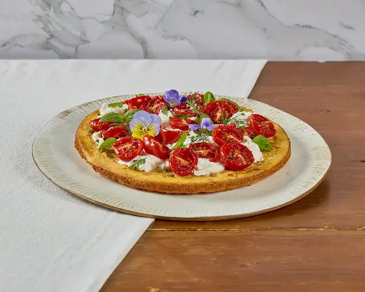 Crispy socca with stracciatella, confit tomatoes and Mediterranean herbs.